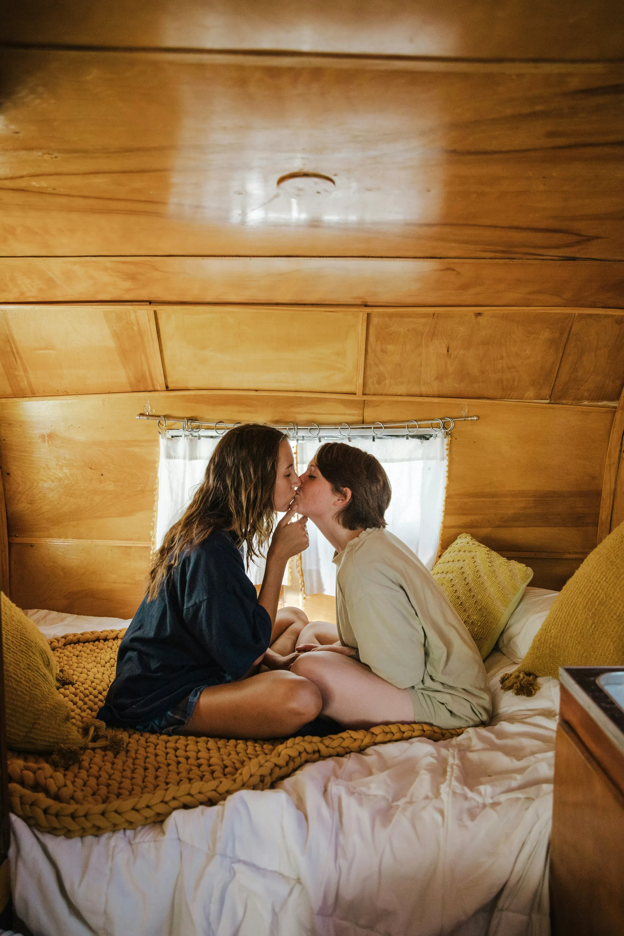 Una pareja besándose en un cuarto de madera junto a la ventana