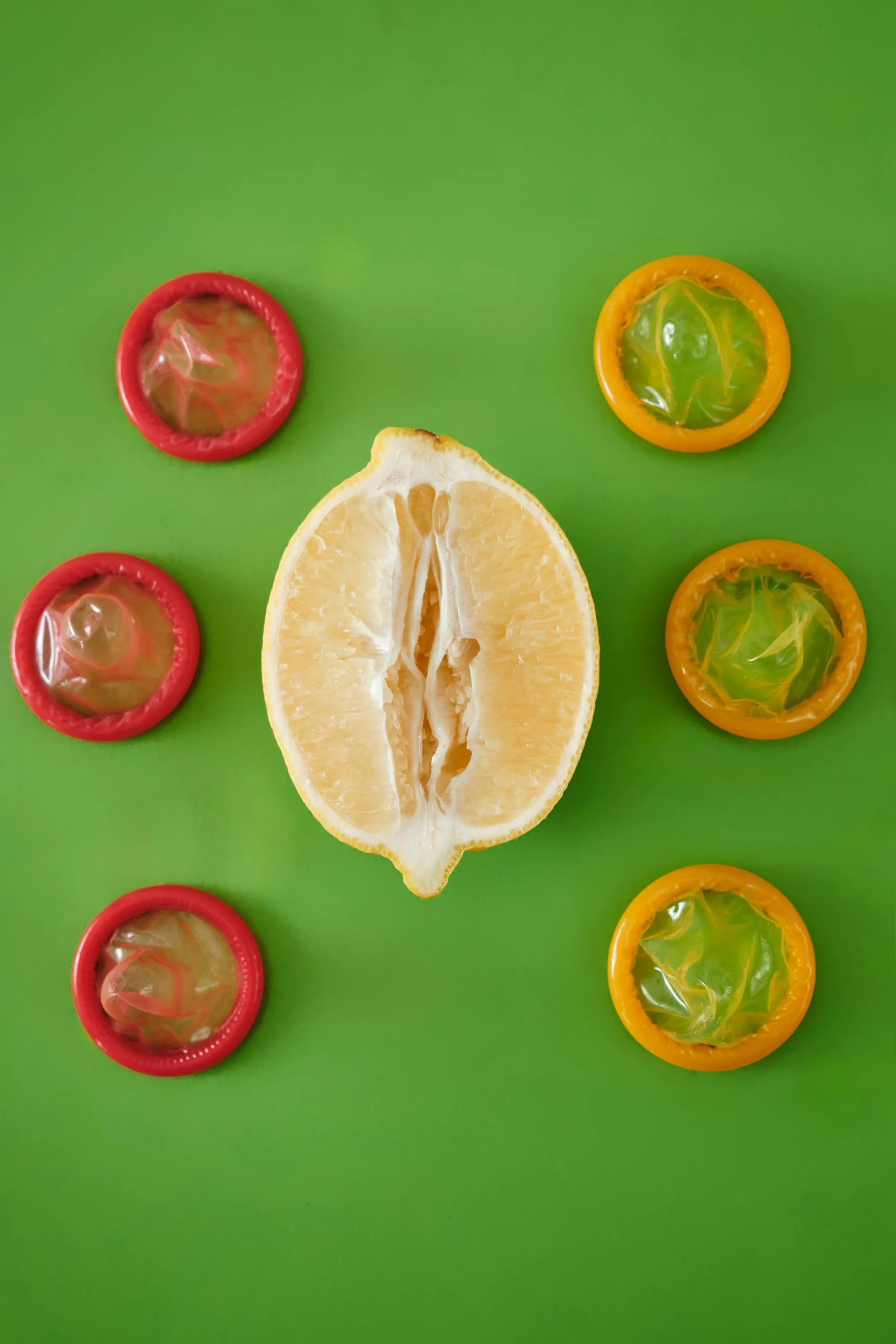 Una fruta cítrica partida rodeada de condones de colores