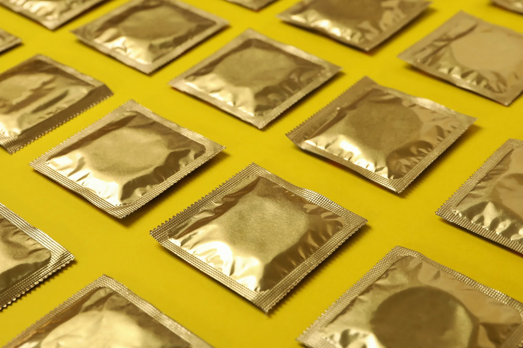 Una cuadrícula de condones dorados sobre fondo amarillo